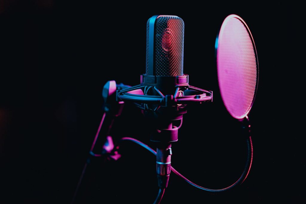 Close-up image of a condenser microphone with a pop filter in a studio setting, featuring atmospheric lighting.